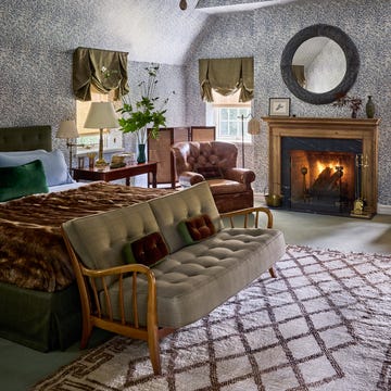 Cozy bedroom with vintage decor, featuring a fireplace and seating area.