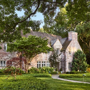 Historic stone house with landscaped garden and porch.