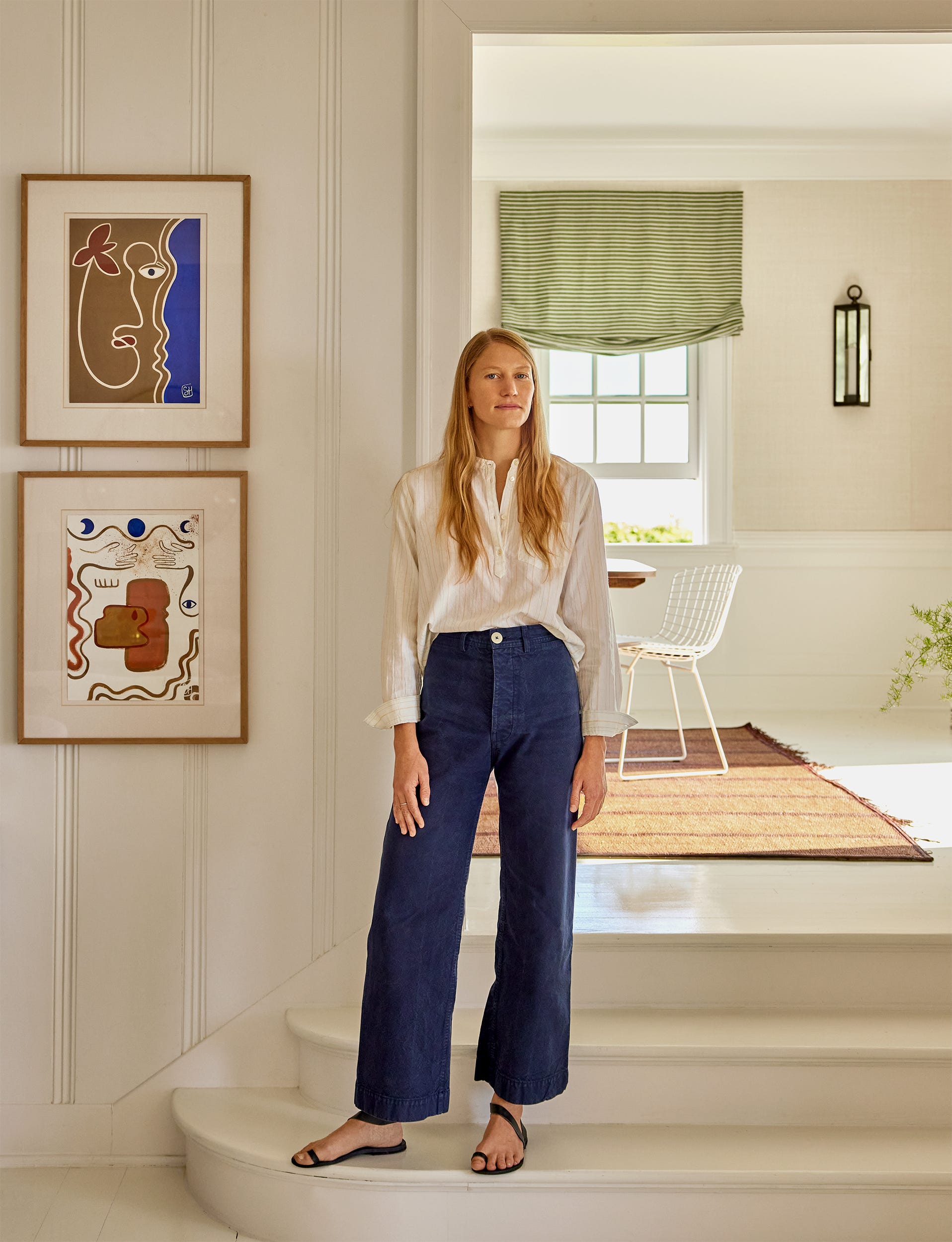A person standing in a modern interior space with art on the walls. A person standing in a modern interior space with art on the walls.