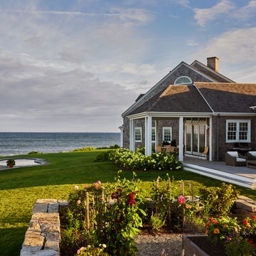 Coastal property featuring a house, a small shed, and a landscaped garden.