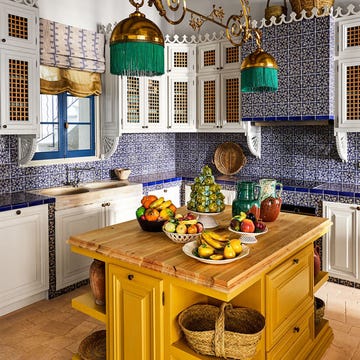 Brightly colored kitchen featuring an island with assorted fruits and decorative elements