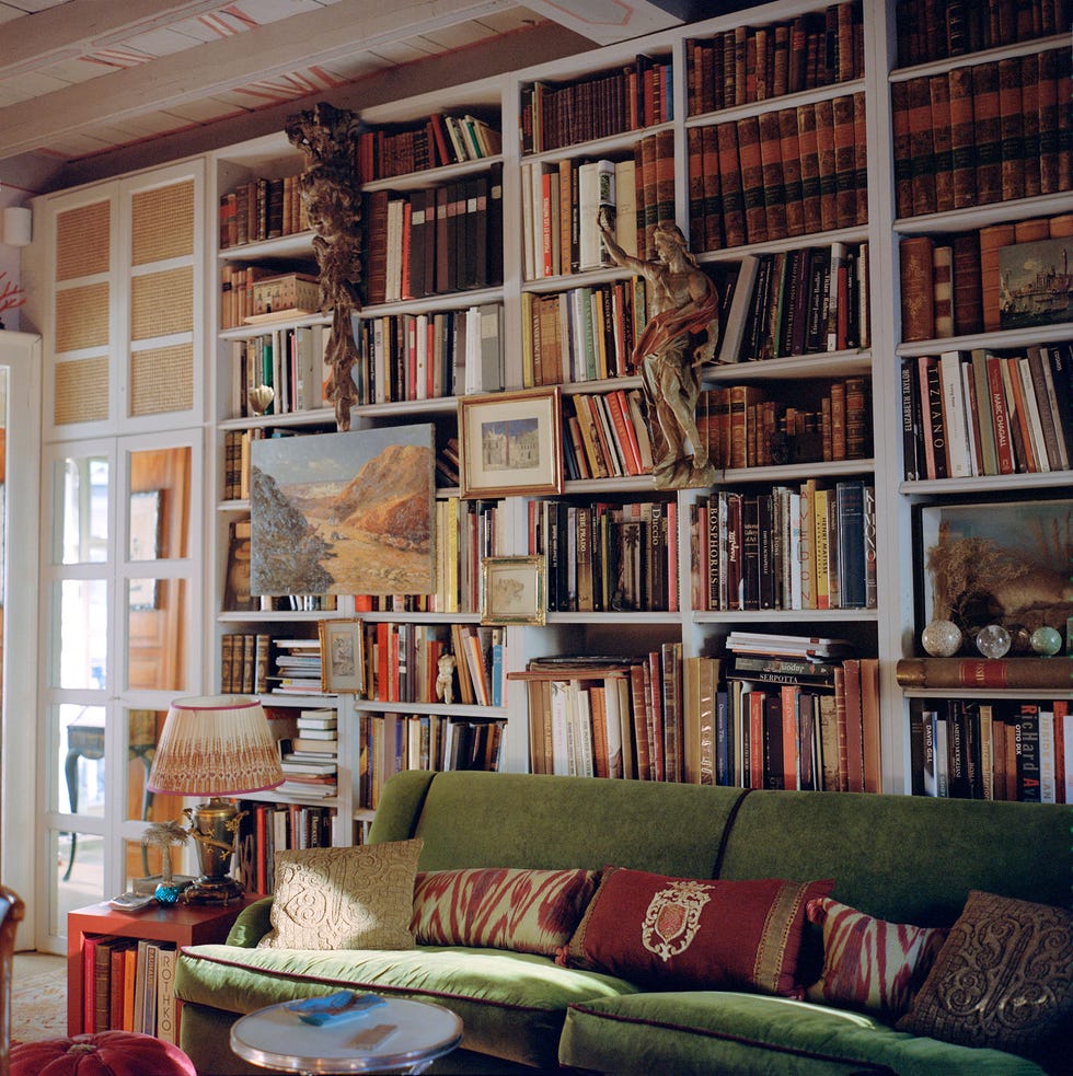 Living room with a green sofa, bookshelf, and decorative elements. Living room with a green sofa, bookshelf, and decorative elements.
