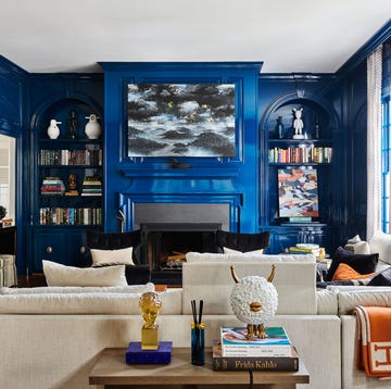 a living room with a fireplace mantel painted a rich blue with an abstract artwork in a similar color palette hanging above