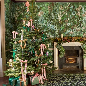 a holiday scene featuring a decorated christmas tree fireplace and floral wallpaper