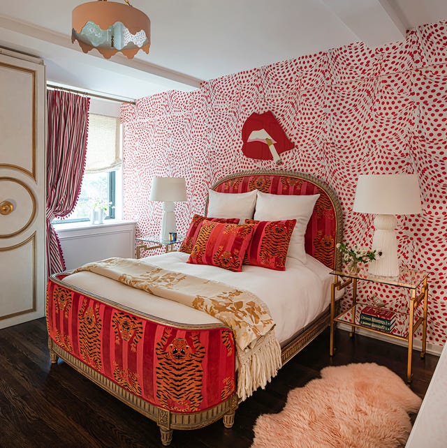 bedroom with a empire styled bed with red striped velvet footboard with tiger print and matching oval headboard and pills with white sheets and a glass side table and white lamp and dark wooden floor