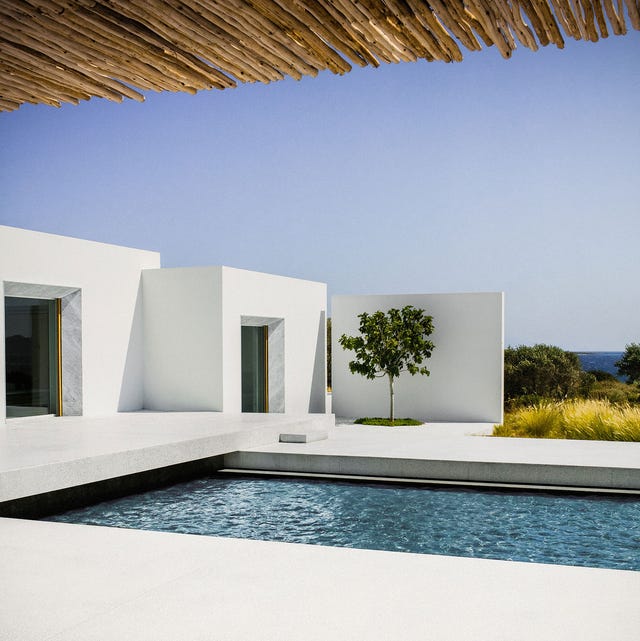 a modern white block house with a pool and views of the ocean beyond