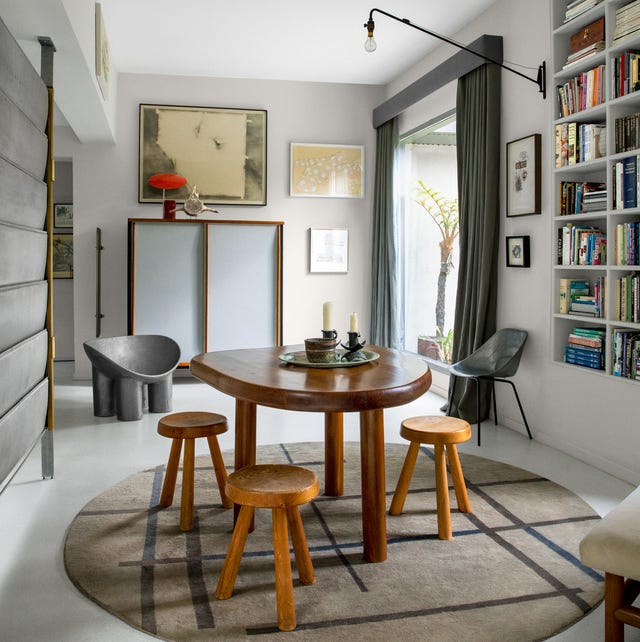 clean white dining area with natural style three legged dining table and low wood three legged stools and a round geometric r