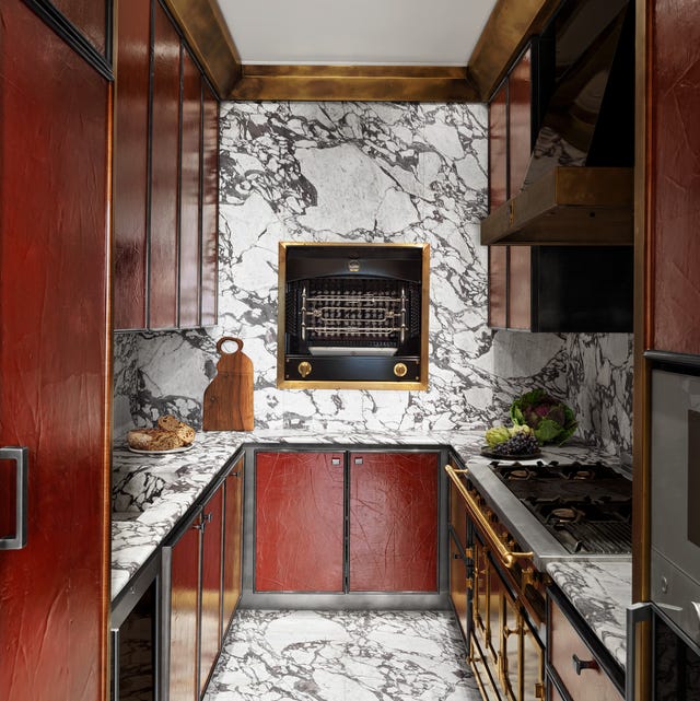 long galley kitchen with grey and white marble floor and counter and walls and red cabinets with some gold hardware