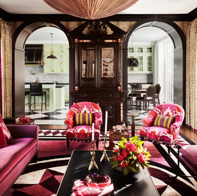 dramatic living room with rounded archways and red patterned modern southwest upholstery on chairs and a plum red velvet on the sofa and a long black cocktail table and a large domed light fixture at top