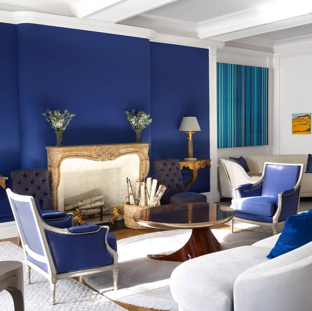 a room with blue walls and matching chairs and white sofa and carpet and gilded tables with lamps