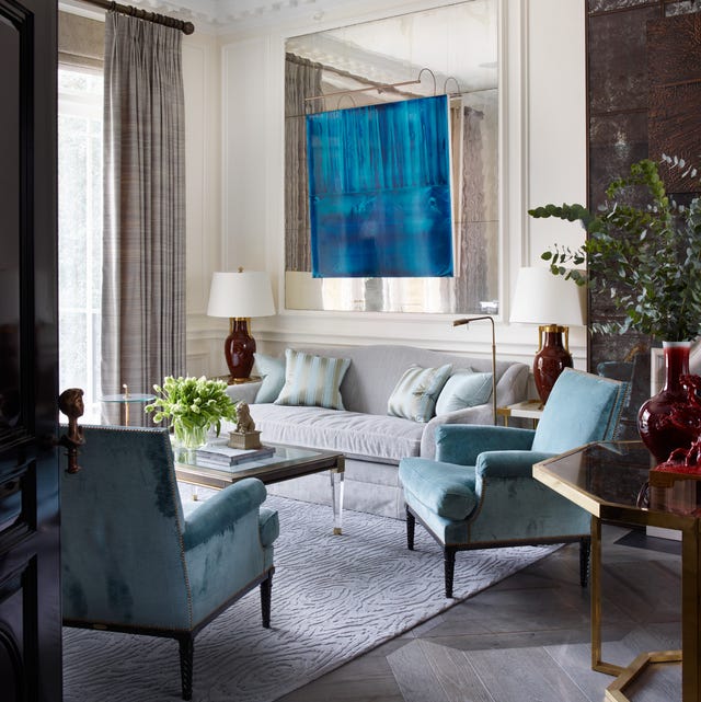 living room with large aqua bluish painting at center over a pale blue velvety sofa and two slightly darker blue chairs flanking a wood and lucite cocktail table