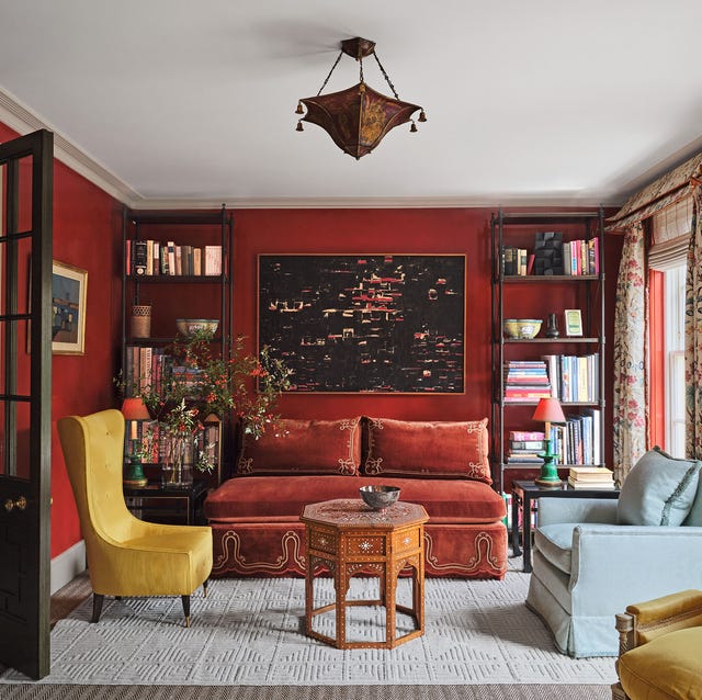 a red painting living room with a red sofa flanked by etageres and small yellow chair and a light blue love seat and a small octagon table as a cocktail table