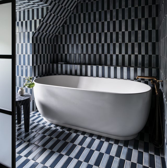 black and grey skinny tile bathroomwith a white standalone tub against the back wall