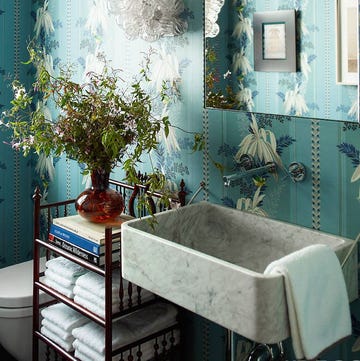 bathroom with blue floral wallpaper, black standalone shelf, marble sink, and bouquet
