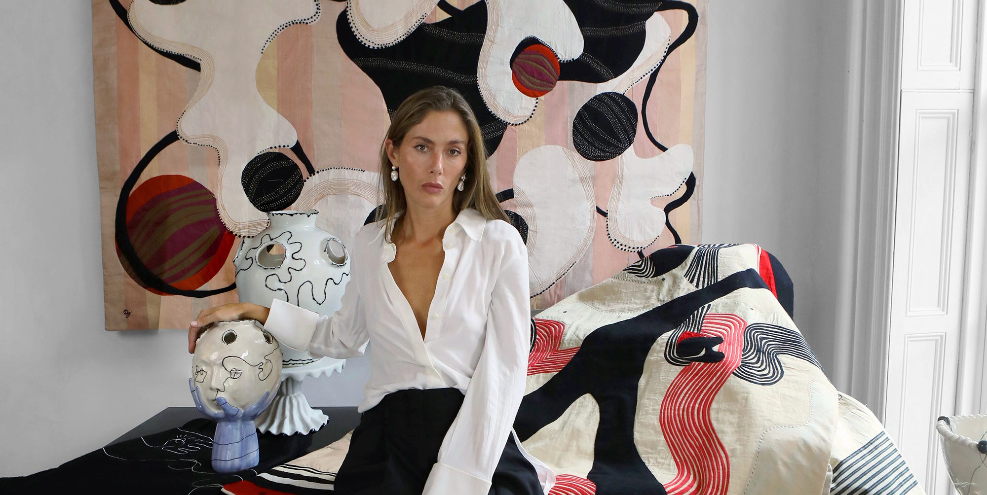 artist quentin jones sits with tapestries and sculptures.