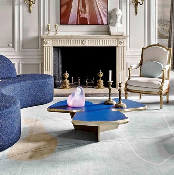 salon de estilo clasico con chimenea, sofa curvo azul oscuro y un busto
