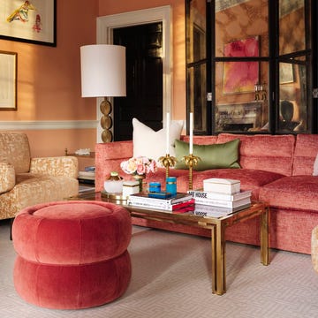salon decorado con un sofa coral sillones dorados y puf rosa