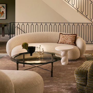 salon con sifa blanco, mesas de centro, sillon verde, escalera y chimenea