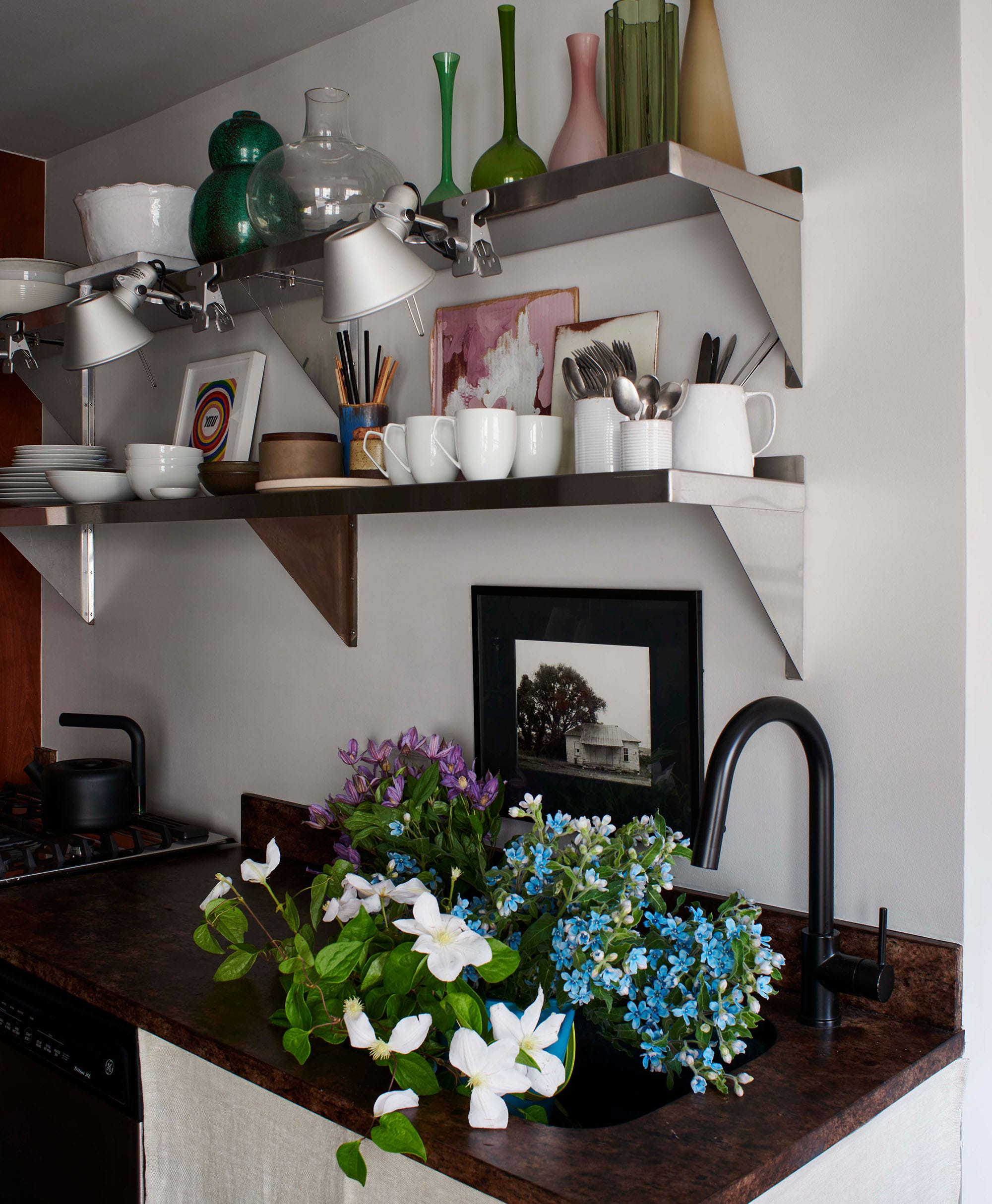 a kitchen with stainless steel shelves full of cookware and flowers in the sink