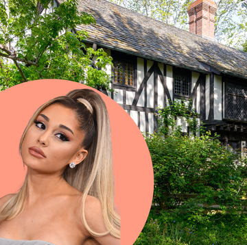 a historic house surrounded by greenery with a person in front